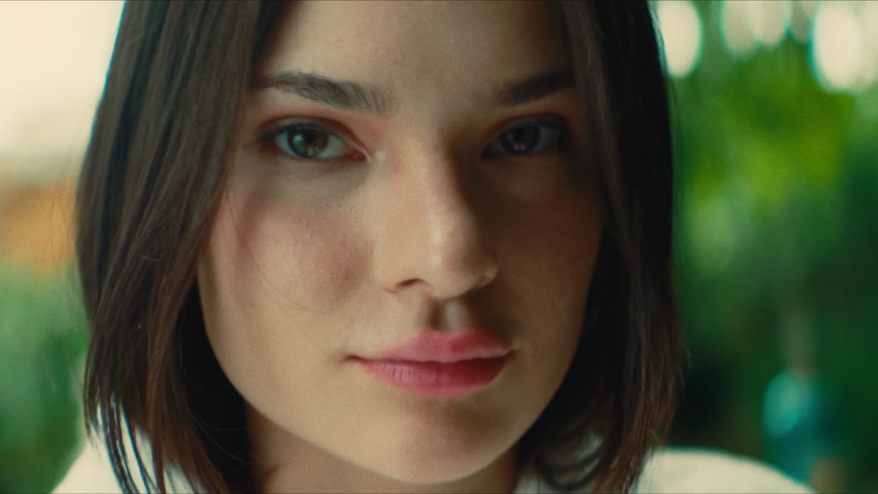 A portrait of a woman with a dark bob against green bokeh